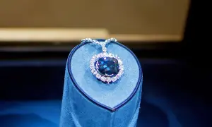 Niebieski diament Hope, otoczony mniejszymi kamieniami, lśni na aksamitnym postumencie.