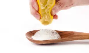 Domowy sposób na czyszczenie srebra kwaskiem cytrynowym. Sok z cytryny reaguje z proszkiem na łyżce, tworząc pianę.