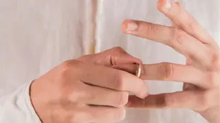 Mężczyzna zdejmuje złotą obrączkę męską z palca.