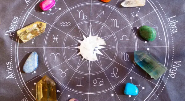 Kamienie szlachetne, w tym lapis lazuli, ułożone wokół znaku zodiaku na czarnym tle.
