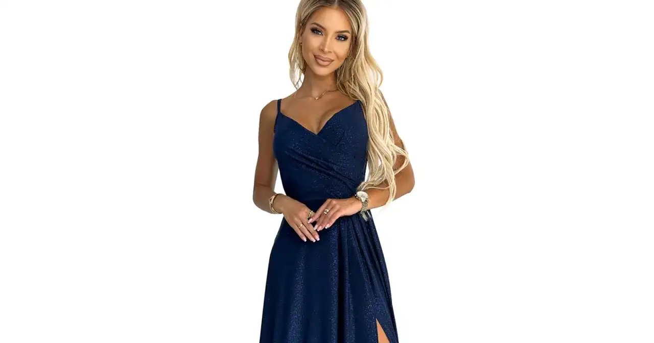 Elegancka kobieta w błyszczącej, granatowej sukience, prezentująca subtelną biżuterię do niebieskiej sukienki: złoty naszyjnik, bransoletki i pierścionki.