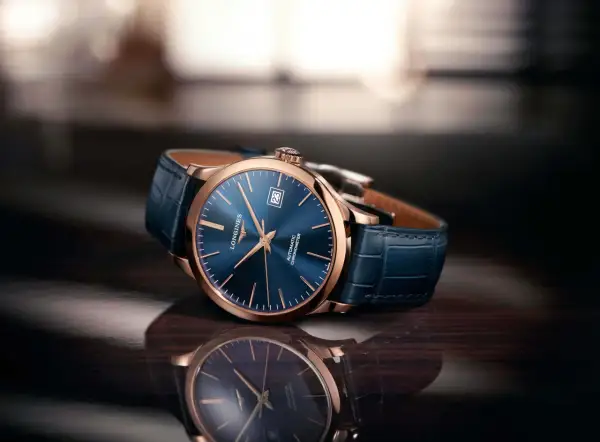 Elegancki zegarek damski rose gold z granatową tarczą i skórzanym paskiem, odbijający się w błyszczącej powierzchni.