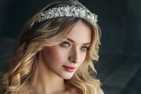 Piękna kobieta z burzą blond włosów, ozdobiona bogato zdobionym diademem ślubnym.