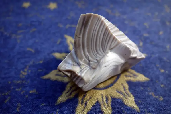 Krzemień pasiasty, niczym znak zodiaku, lśni na tle granatowego materiału z motywem słońca.
